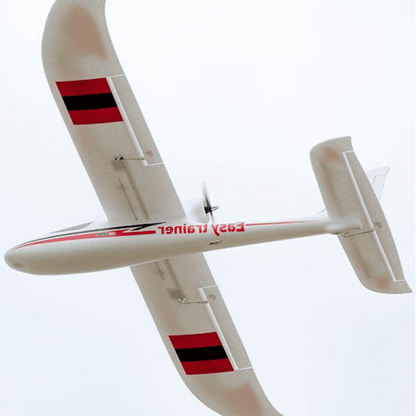 FMS 1280mm Easy Trainer RC plane with red and black wing accents, flying with a clear sky background.