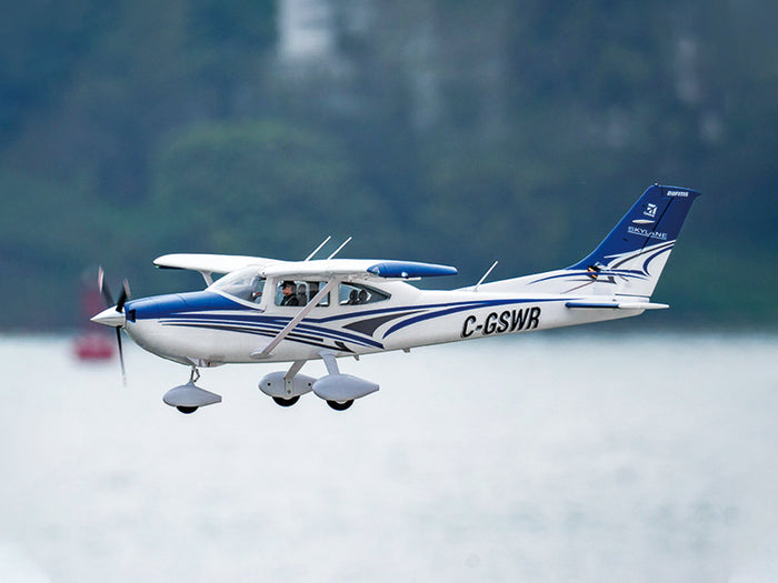 Blue and white Cessna 182 RC airplane soaring in the sky