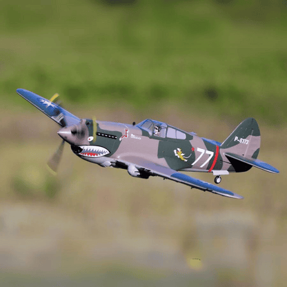 FMS 980mm P-40B Flying Tiger aircraft in flight, featuring shark mouth nose art and '77' marking.