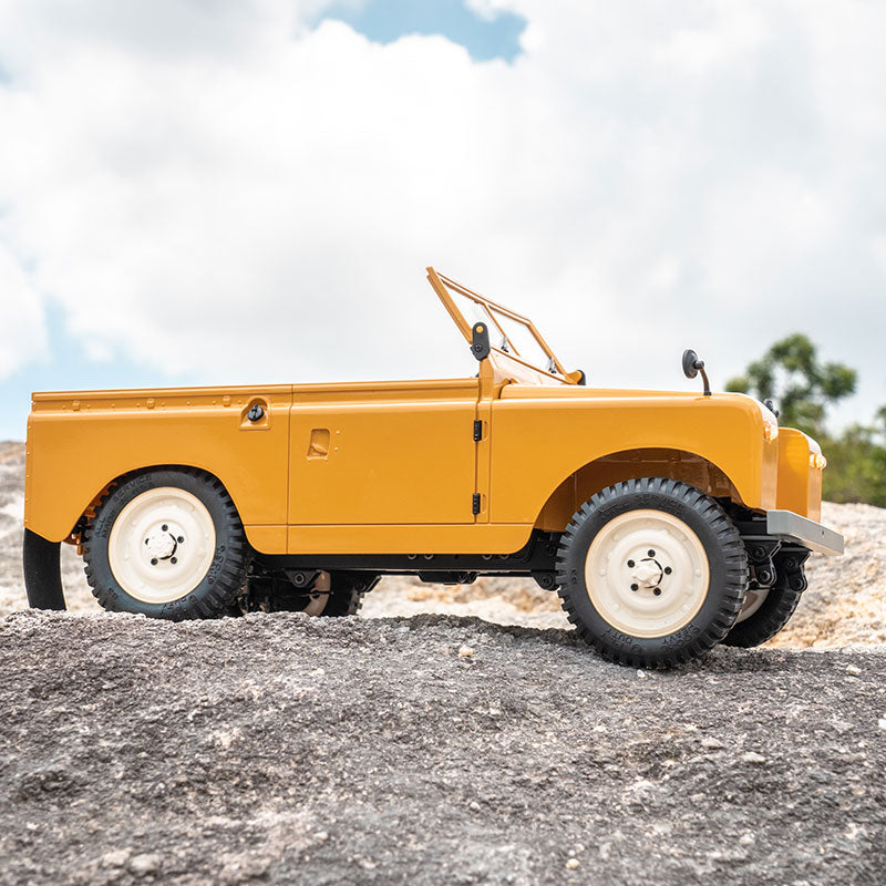 Yellow 1:12 FMS Land Rover Series II RTR toy vehicle on rocky terrain