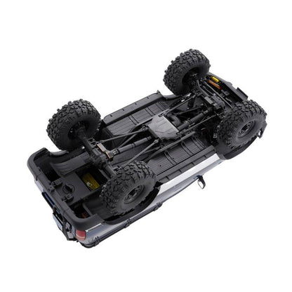 FMS FCX10 PRO LC80 RS V2 underside view: chassis, drivetrain, and large off-road tires.