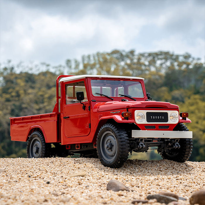 FMS 1:12 scale red Toyota FJ45 pickup truck RTR with white roof, detailed grille and off-road tires on gravel