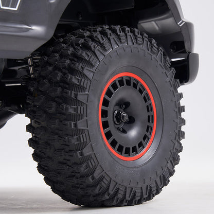 FMS 1:10 Canyon RS off-road RC car wheel with aggressive tread tire and red-accented black rim.