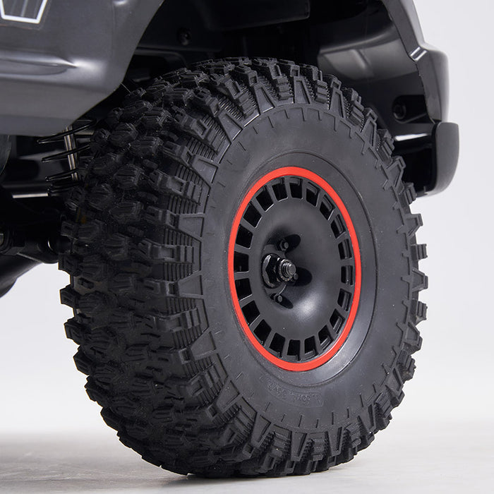 FMS 1:10 Canyon RS off-road RC car wheel with aggressive tread tire and red-accented black rim.