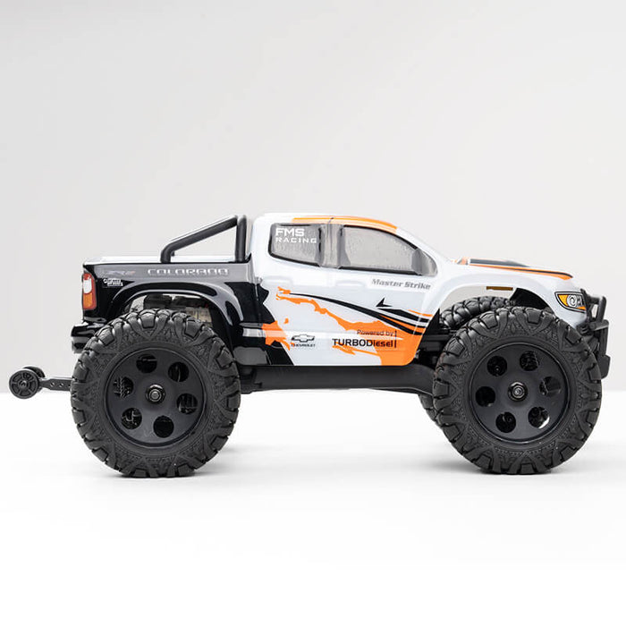 FMS 1:24 FMT24 Chevrolet Colorado Monster Truck RTR in white with orange and black graphics, featuring large off-road tires.