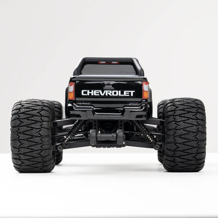 Black FMS 1:24 FMT24 Chevrolet Colorado monster truck rear view with large tires and suspension
