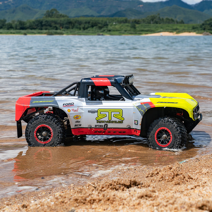 FMS 1:18 Ford Bronco RTR EB RC truck, silver/yellow, with Nitto tires, on wet sand.