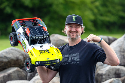 Man proudly holding FMS 1:7 Ford Bronco RTR EB Brushless 4WD RC car, yellow and white with black accents.