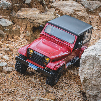 Red ROCHOBBY 1:10 Mashigan RC rock crawler on rocky terrain. Detailed, all-terrain tires, black top.