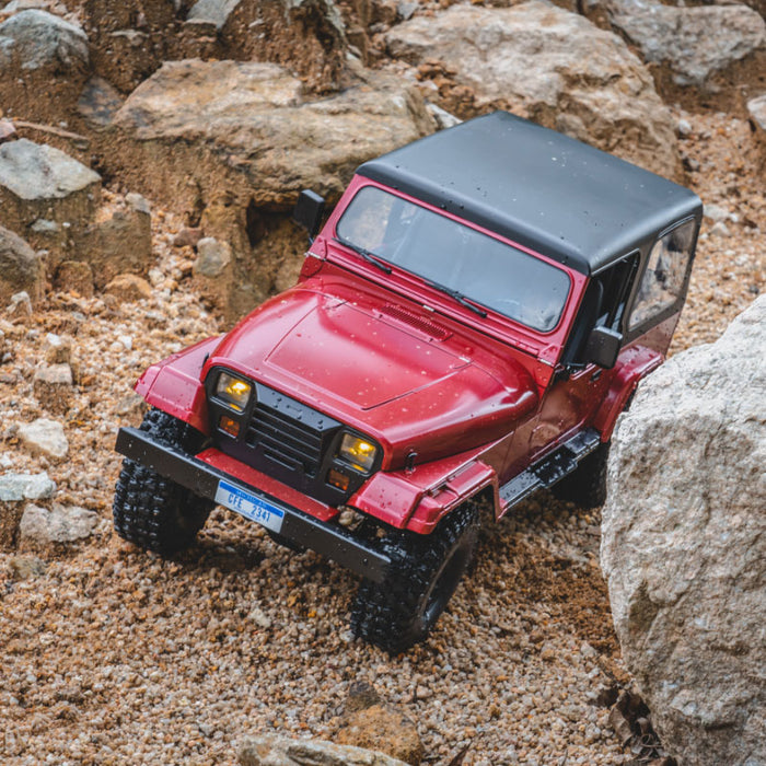 Red ROCHOBBY 1:10 Mashigan RC rock crawler on rocky terrain. Detailed, all-terrain tires, black top.