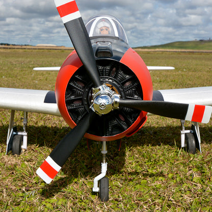 Red and black FMS 1400mm T-28D Trojan V4 PNP RC airplane on grass, front view.