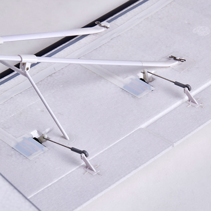 FMS 1300mm PA-18 Super Cub RC airplane wing underside with servo horns and landing gear struts.