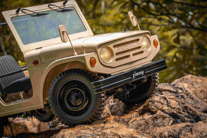 FMS 1:6 scale brown Suzuki Jimny RC car with detailed exterior and off-road tires climbing rocky terrain.
