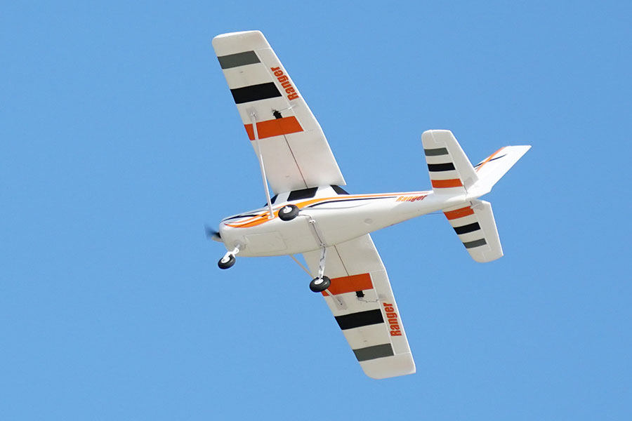 FMS 850mm Ranger RC airplane in flight with orange and black stripe accents.