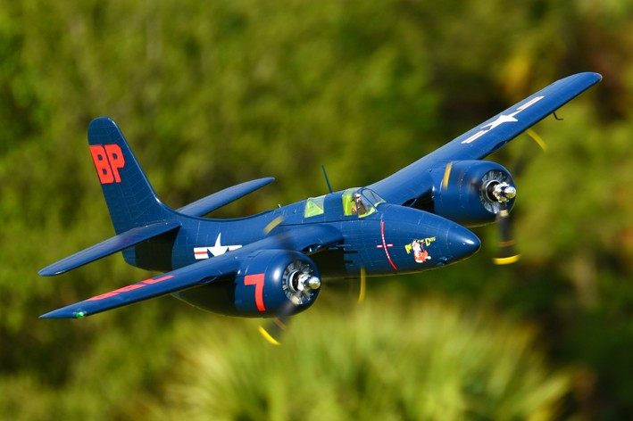 FMS 1700mm F7F Tigercat RC airplane in flight, blue livery with red "BP" tail marking and "7" on engine nacelle.
