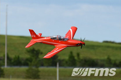 Red FMS 1100mm PC-21 Pilatus PNP RC airplane in flight with white accents and FMS logo.