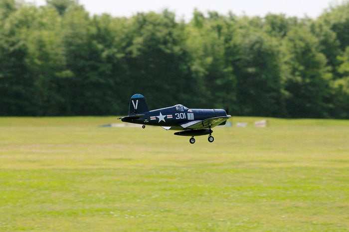 FMS 800mm F4U Corsair V2 RC plane in flight over a grassy field, featuring scale details and the number 301.
