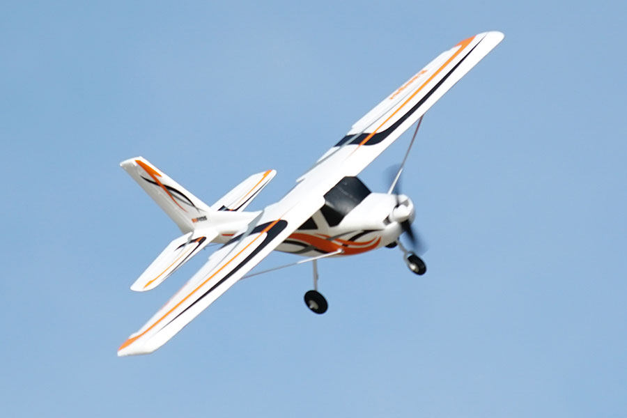 FMS 850mm Ranger RC airplane in flight with white, orange, and black design