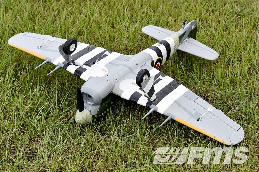 FMS 1100mm Hawker Typhoon PNP model aircraft with black and white stripes on wings, sitting on grass.