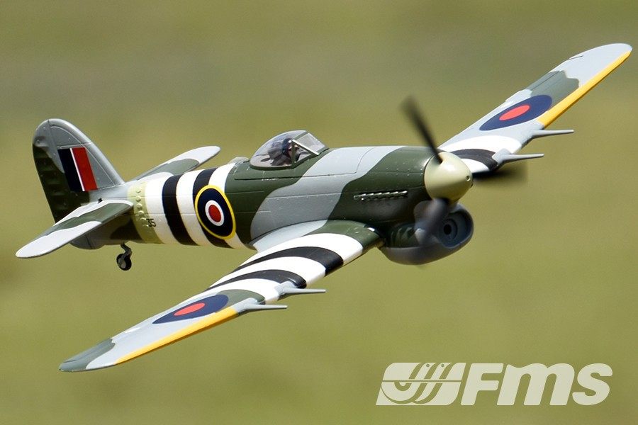 FMS 1100mm Typhoon PNP model airplane in flight, featuring a detailed camouflage paint scheme with black and white stripes.