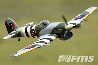 FMS 1100mm Typhoon PNP model airplane in flight, featuring a detailed camouflage paint scheme with black and white stripes.