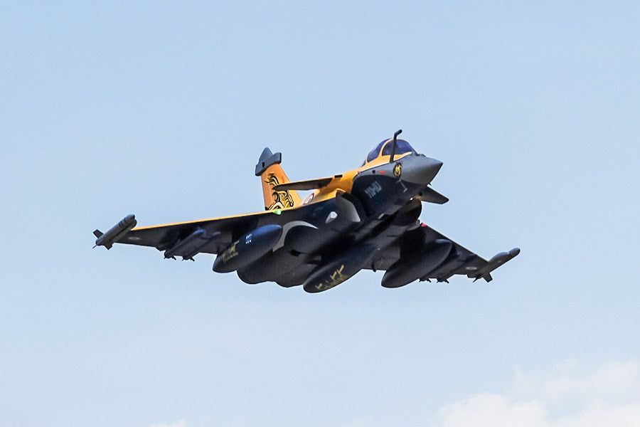 FMS 80mm Rafale PNP jet in flight, featuring yellow and blue livery with stylized tiger graphics on tail